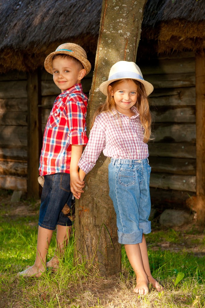 Boy and Girl in Hats Holding Hands by Tree