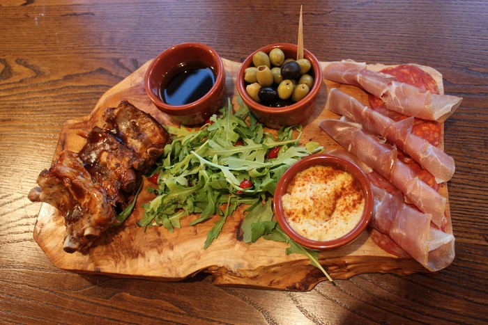 Charcuterie board with ribs, ham, olives, and dip