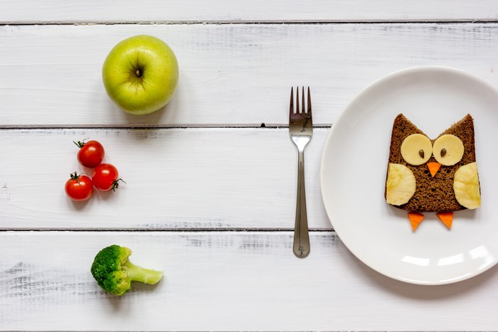 Owl sandwich with apple, tomatoes, and broccoli on wood planks