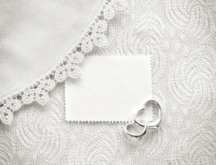 Two hearts pendant on a textured surface with lace
