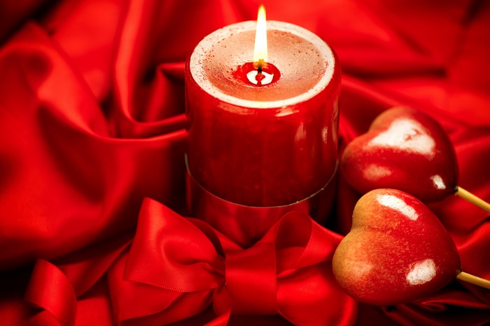 Red candle with heart candies and ribbon