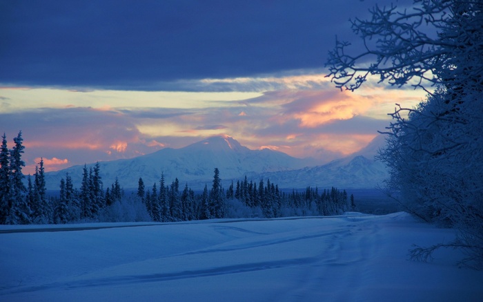 Snowy landscape with mountains and colorful sunset sky