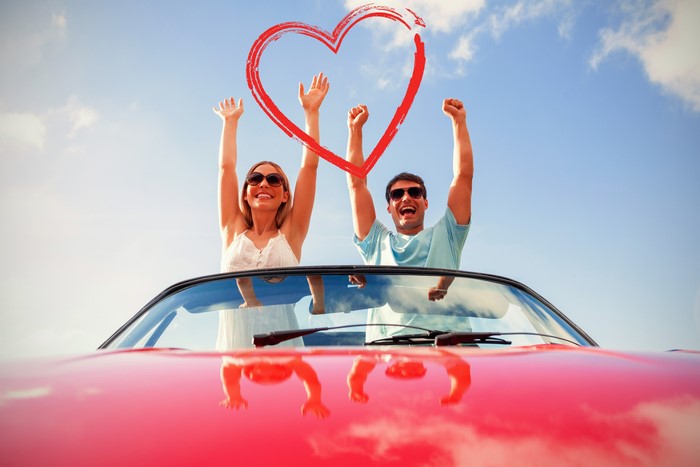 Couple celebrating in a convertible with a heart