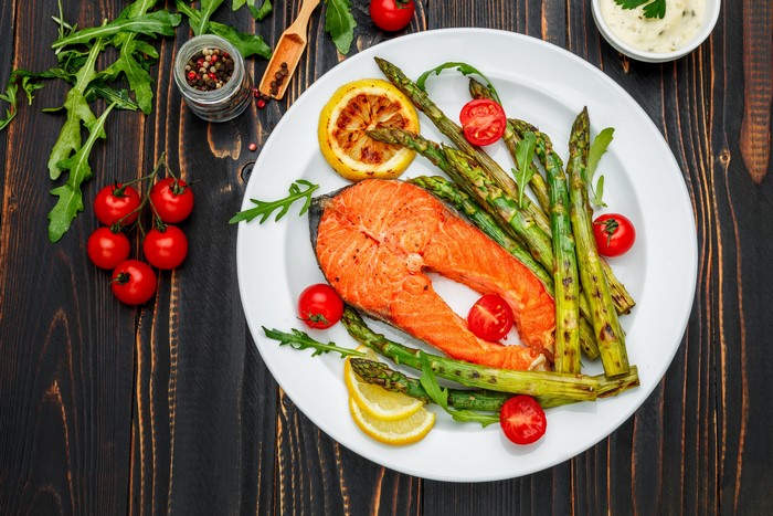 Salmon steak with asparagus, tomatoes, and lemon