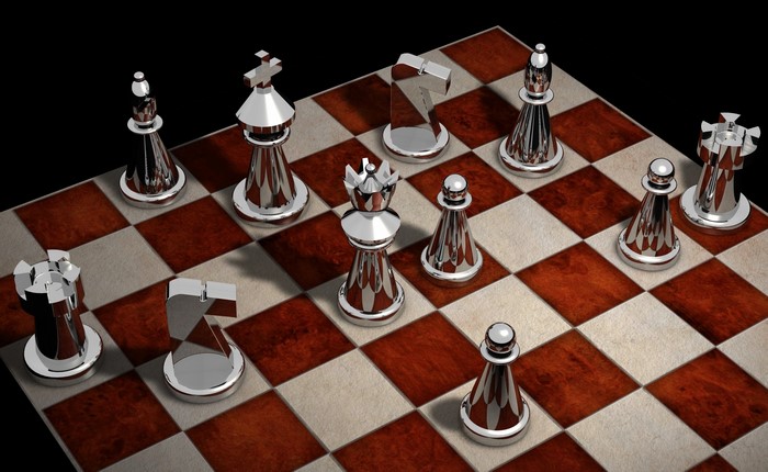 Silver chess pieces on a wooden chessboard