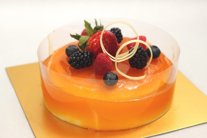 Orange gelatin dessert with berries and white chocolate garnish
