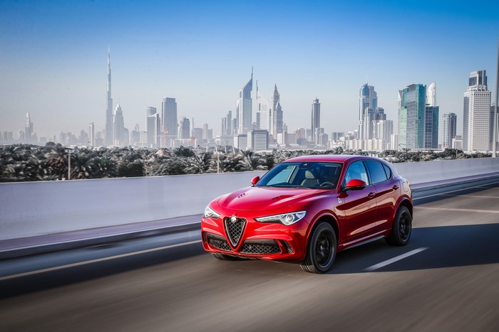 Red Alfa Romeo Stelvio Quadrifoglio in motion with Dubai skyline