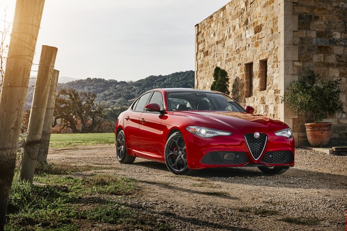 Red Alfa Romeo Giulia parked near a stone building
