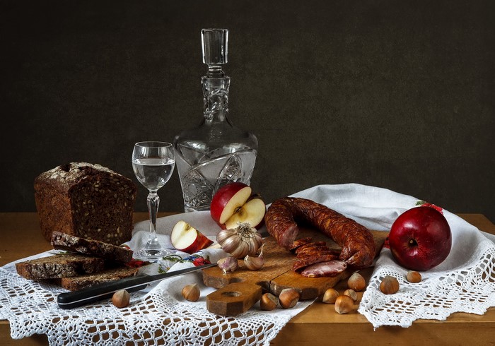 Still life with sausage, bread, apples, nuts, and vodka