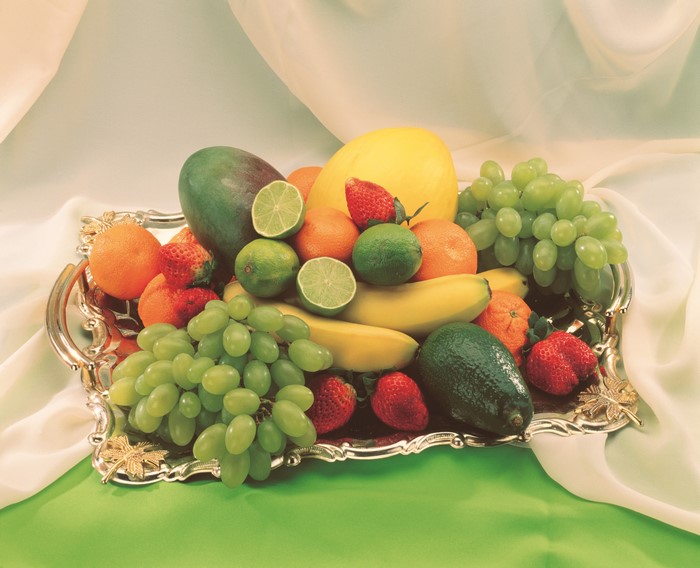 Fruit platter with grapes, avocado, strawberries, mango, limes, oranges, and bananas