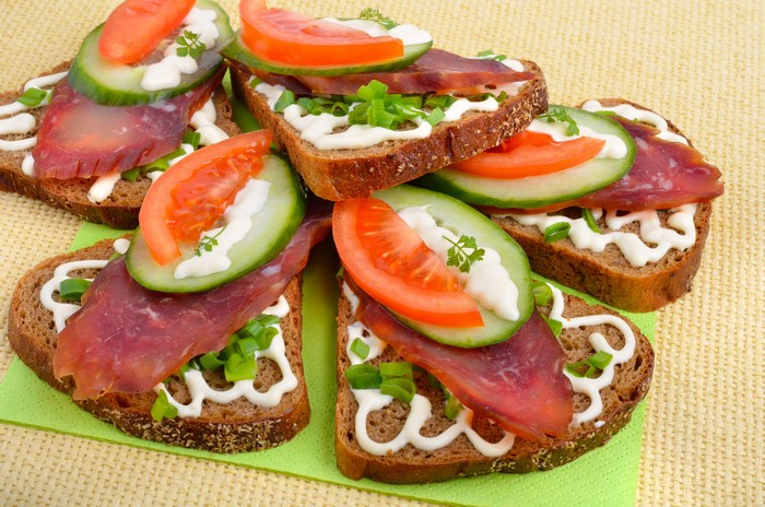 Open-faced sandwiches with sausage, cucumber, and tomato