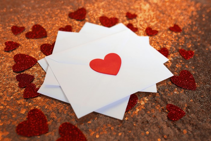 White envelopes with red heart on sparkly background