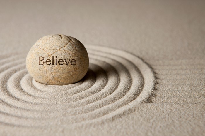 Stone with the word Believe in sand circles