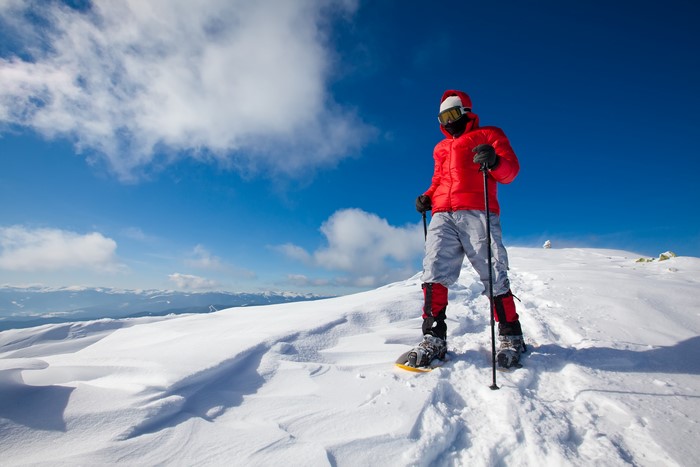 Man in red jacket snowshoeing on a snowy mountain