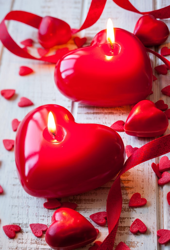 Red heart-shaped candles with ribbons and confetti