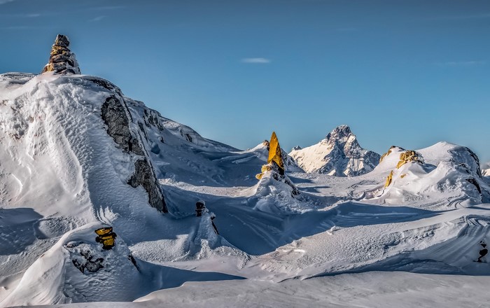 Snowy Alps mountains with rock formations under a clear blue sky