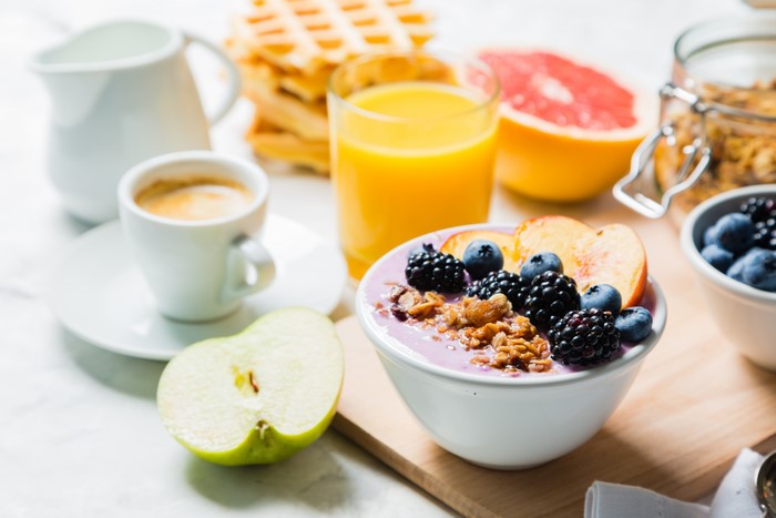 Breakfast with waffles, juice, coffee, and fruit bowl