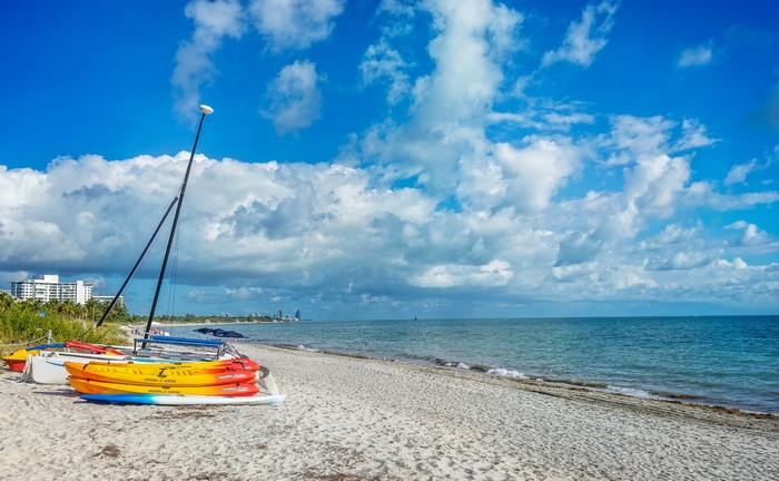 Kayaks and sailboats on a sandy beach in Florida