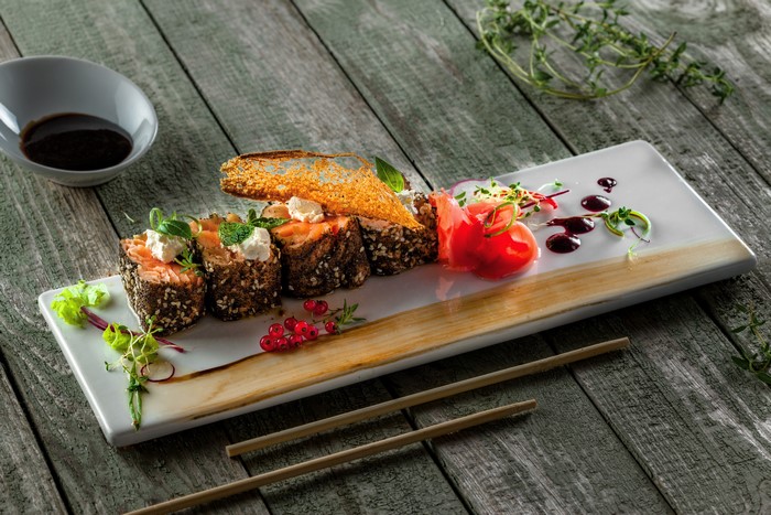 Sushi with salmon, cheese, and currants on a wooden table