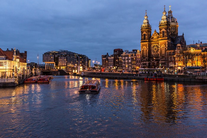 Amsterdam canal at dusk with boats and Basilica of Saint Nicholas