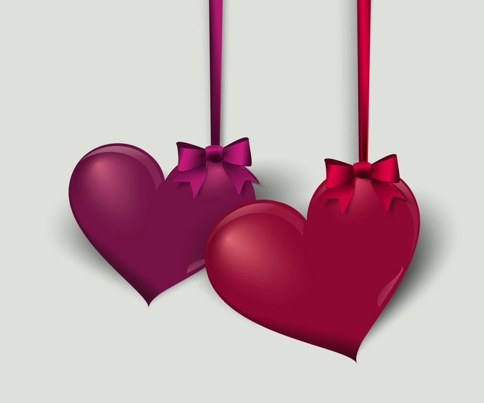 Two hearts with bows on gray background