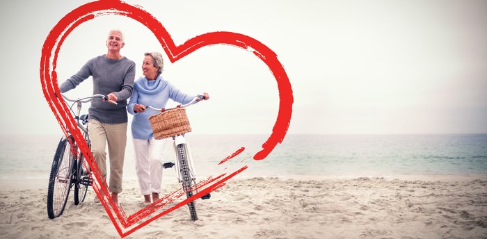 Elderly Couple with Bicycles on Beach with Heart