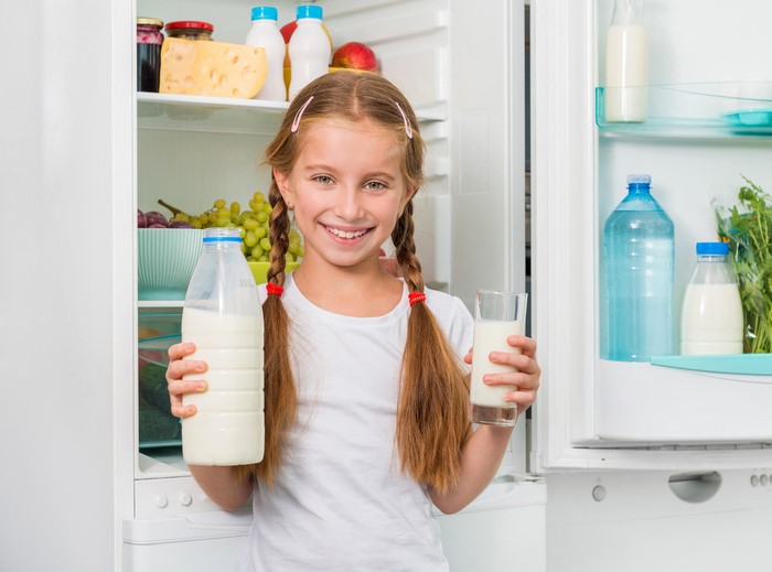 Smiling Girl Holding Milk Bottle and Glass