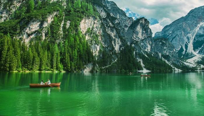 Two people in a boat on a lake with mountains and trees