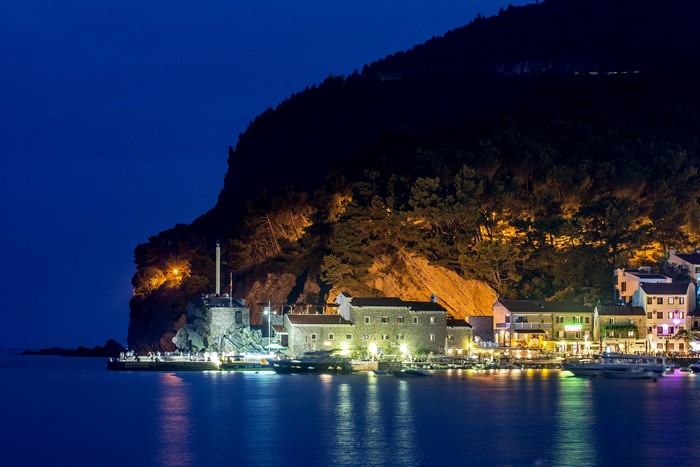 Night view of Budva, Montenegro with illuminated buildings and bay