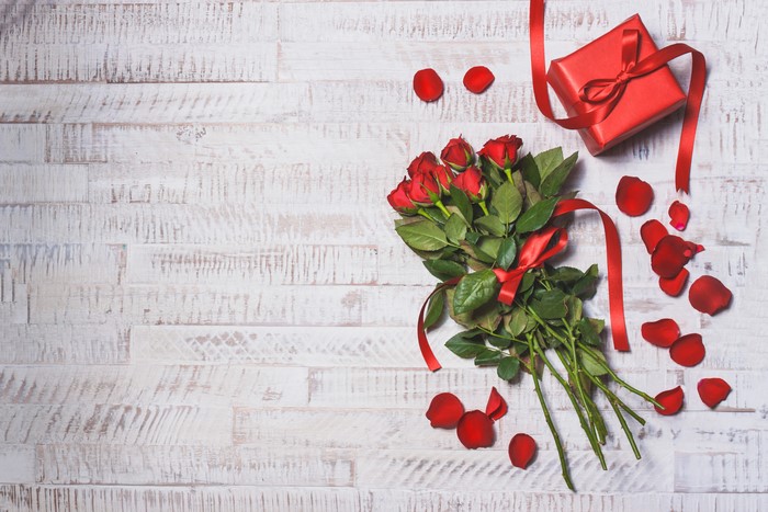 Red roses bouquet and gift on wooden planks