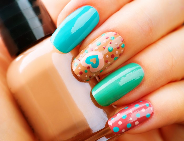 Macro shot of a hand with colorful nail art and a nail polish bottle