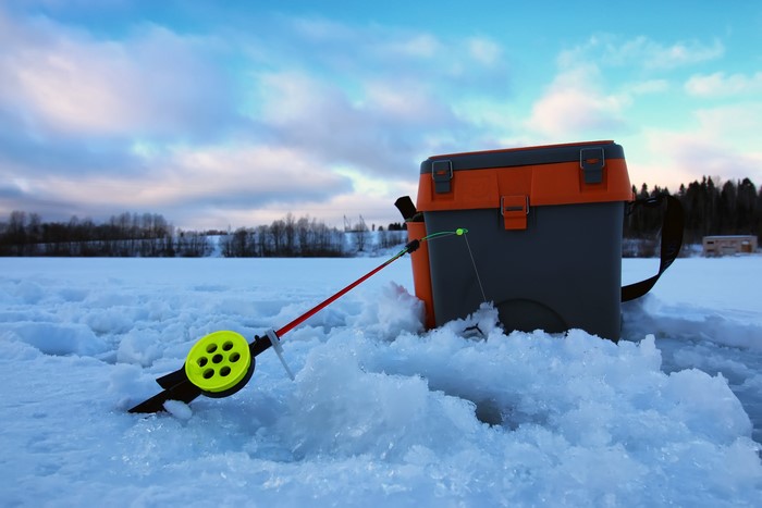 Ice fishing rod and tackle box on snow
