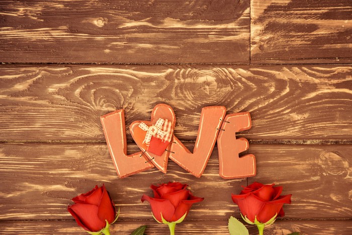 Love letters and red roses on wood planks