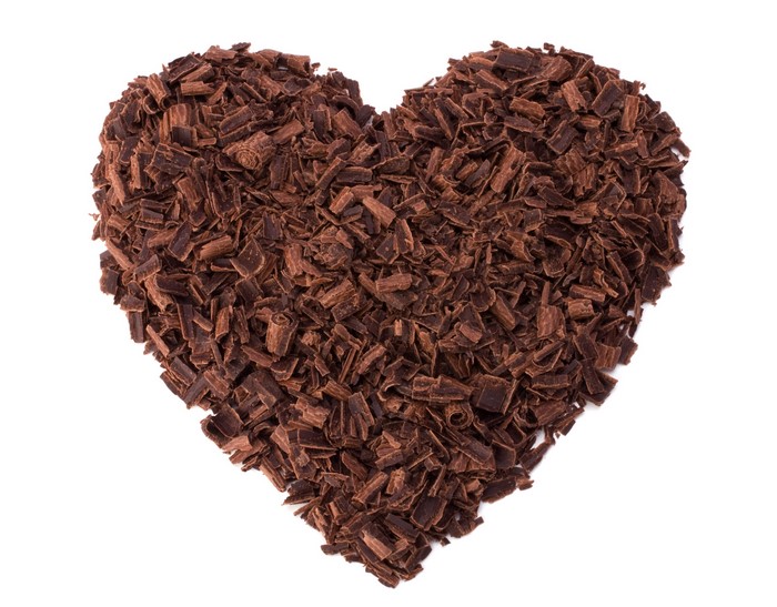 Heart shape made of chocolate shavings on white background