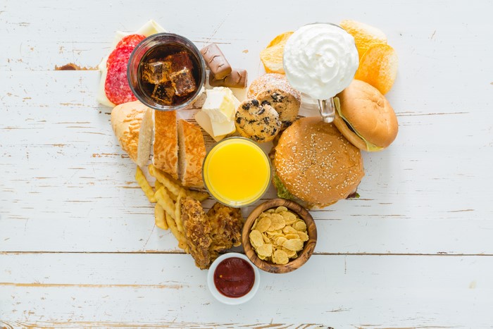 Heart shape of unhealthy food including burgers, fries, and sweets