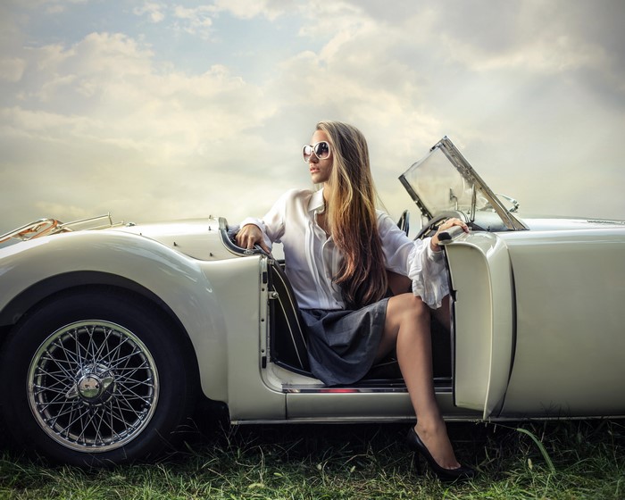 Blonde woman in sunglasses sitting in a vintage convertible