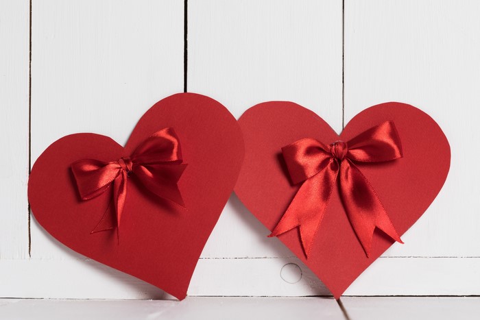 Two red hearts with red bows on wood planks