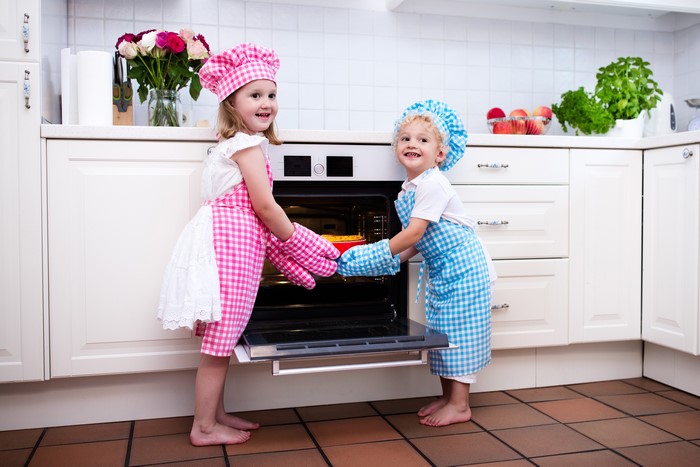 Children in chef uniforms baking in a kitchen