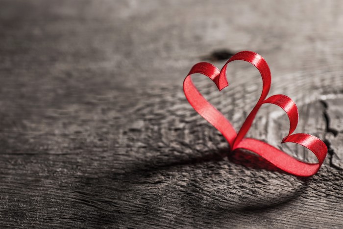 Red ribbon heart on wooden background