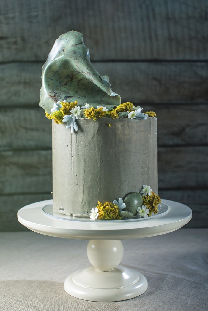 Gray frosted cake with stone and floral decoration