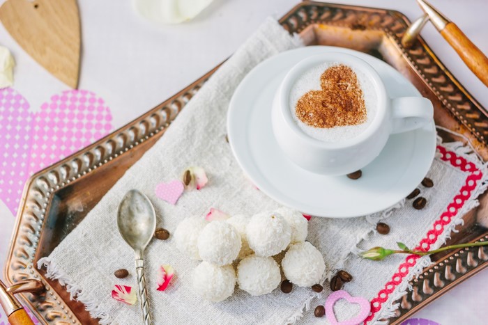 Coffee with heart art and coconut candies on a tray