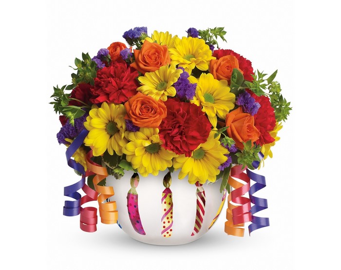 Birthday flower arrangement in a vase with candles and streamers