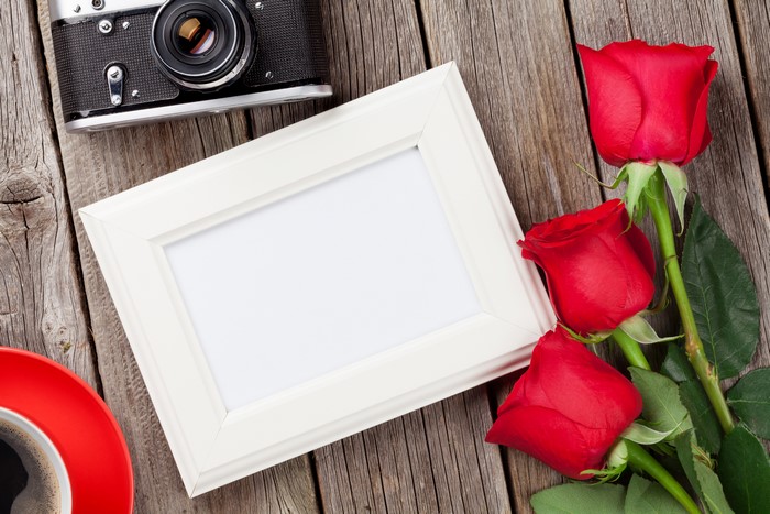 Red roses, camera, photo frame, and coffee on wood
