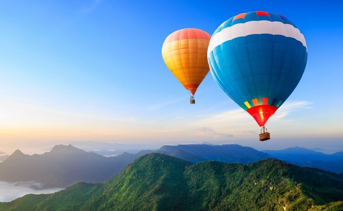Two hot air balloons flying over mountains