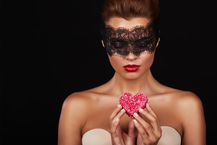 Woman in Lace Mask Holding Heart Cookie