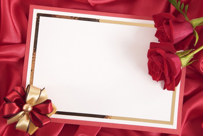 Greeting card with red roses and bow on red satin