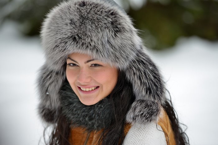 Woman in a fur hat smiling in the snow