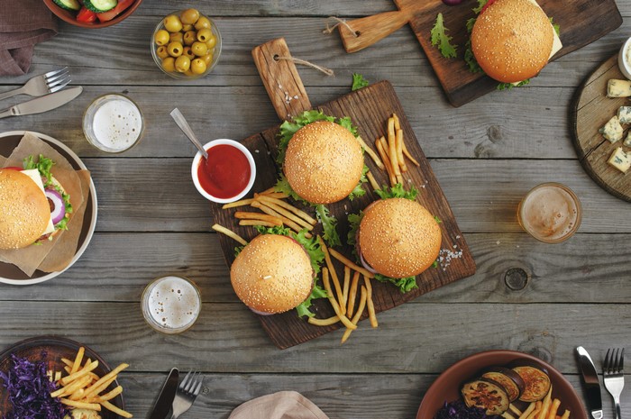 Hamburgers, French Fries, Olives, and Beer on Wood