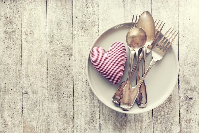 Plate with heart and cutlery on wood planks