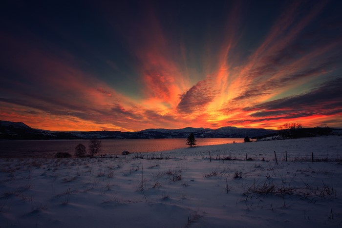 Winter sunset over a snowy lake with dramatic clouds